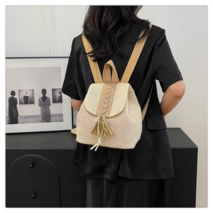 Detail of straw woven backpack with fringe and crisscross pattern worn by a model