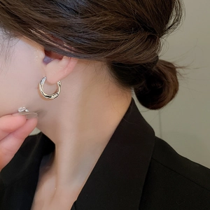Macro shot of silver twisted double hoop earrings with pavé zircons worn by a model