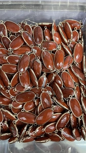 Macro shot of faceted red crystal oval connectors with gold plating in bulk storage