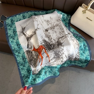 Détail d'un foulard en soie avec illustration de cerf et bordure motif serpent bleu