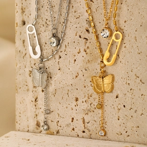 Detail of layered gold and silver butterfly pendant necklaces with crystal accents on stone