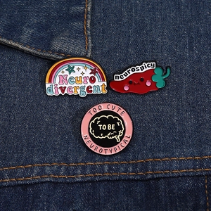 Close-up of neurospicy chili and neurodivergent enamel pins on blue denim jacket pocket