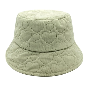 Detail of light green corduroy bucket hat with heart-shaped quilted pattern and texture
