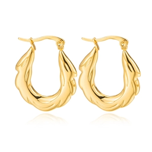 Close-up of golden U-shaped earrings with textured wavy patterns and polished finish