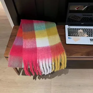 Detail of colorful rainbow plaid scarf featuring long tassels and soft cashmere-like texture