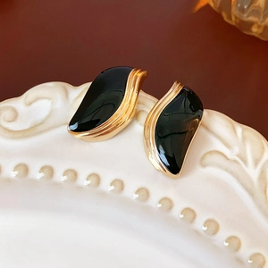 Détails de boucles d'oreilles feuilles vintage or et noir sur assiette en céramique