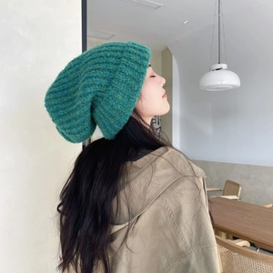 Detailed close-up showing the thick teal cable knit texture and slouchy beanie style