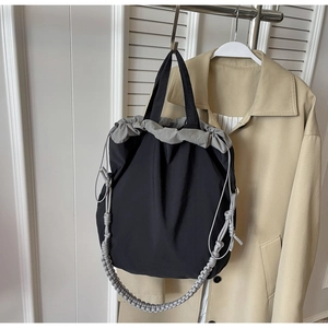 Dettaglio della borsa tote in nylon nero con coulisse grigia e tracolla intrecciata