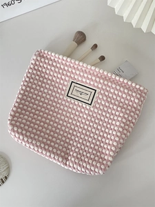 Detail of checkered makeup bag with PLEASANT TIME label and woven fabric texture