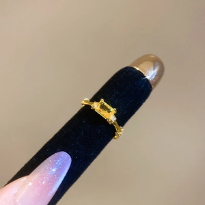 Detail view of gold ring with yellow rectangular gemstone and white diamonds on velvet