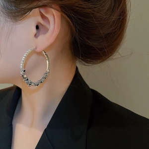 Macro side view of silver hoop earrings with rhinestones worn by a model in a close-up