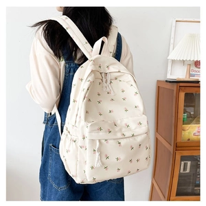 Detail of floral canvas backpack on shoulder showing side pocket and zip decoration