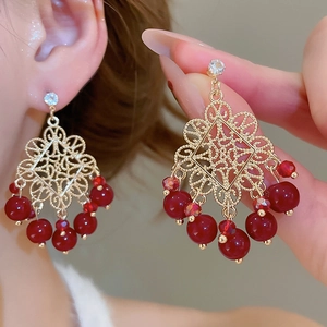 Detail of vintage palace style flower earrings with red beads and tassels for women