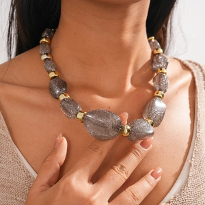 Close-up of gray resin beads with glitter and gold metal rings on chunky necklace
