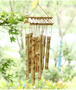 Outdoor shot of a bamboo wind chime with natural brown patterns and wooden roof detail
