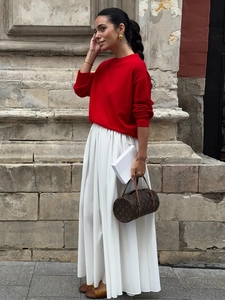 Close-up of a high-waisted white pleated maxi skirt paired with a red knitted sweater
