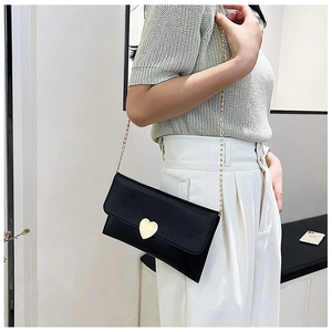 Close-up of black crossbody bag featuring a golden heart buckle and metal chain strap
