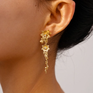Macro shot of gold floral drop earrings with textured petals and center zircon stone