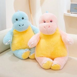 Close-up of soft plush dinosaur pillows in blue and pink on a cozy beige sofa