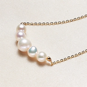 Minimalist freshwater pearl necklace with five white pearls on a gold chain