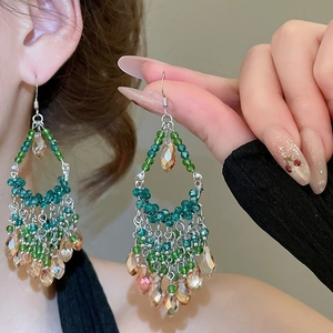 Detail of green and champagne beaded tassel earrings on a model for a luxury look