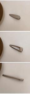 Three minimalist matte dark grey metal hair clips set shown on a beige surface background