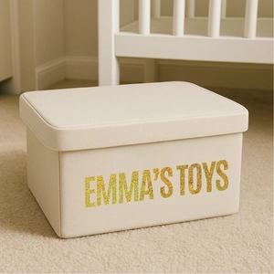 Detail of custom gold glitter letters on cream fabric storage box in a nursery setting
