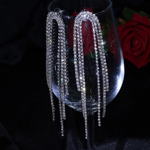 Macro shot of silver-colored long tassel earrings with sparkling rhinestones on a glass