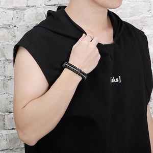 Detail of male model wearing double-layered black woven leather and silver chain bracelet