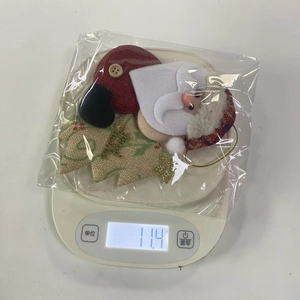Dettaglio di un pupazzo di Babbo Natale in tessuto del peso di 11,4 g sulla bilancia