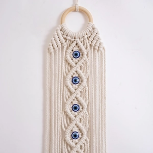 Detail of bohemian hand-woven cotton tapestry with blue evil eye beads and wood ring