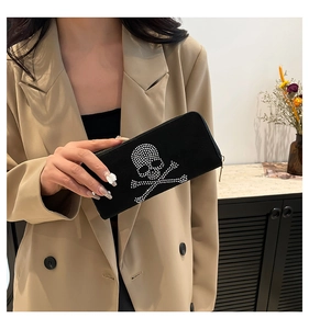 Detail of black suede long wallet featuring a large rhinestone skull and crossbones design