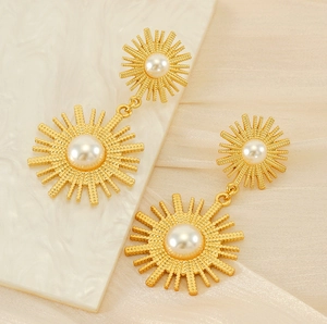Gros plan de boucles d'oreilles soleil dorées avec perles blanches sur velours