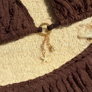 Detail of brown textured bikini with starfish, pearl pendant and rhinestone ring