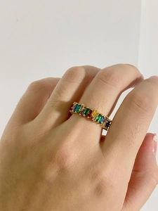 Close-up of golden ring with rainbow baguette-cut zircons worn on finger