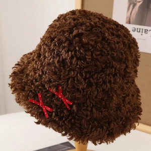 Chapeau bob en peluche marron avec nœuds rouges à pois sur support en bois