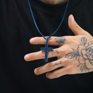 Detail of dark blue stainless steel cross pendant with hollow design on snake chain