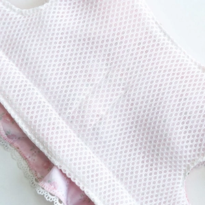 Close-up of pink floral fabric with white honeycomb mesh and delicate lace trim detail