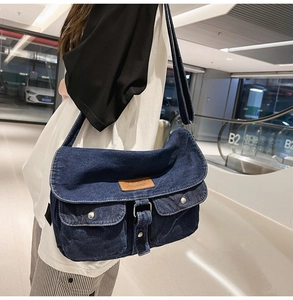 Dettaglio della borsa a tracolla in denim blu con toppa in pelle marrone e due tasche