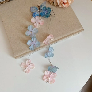 Detail of fabric butterfly hair clip with silk flowers, pearls and long chain tassels