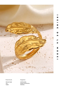 Macro detail of golden double leaf ring with textured veins on white stone surface