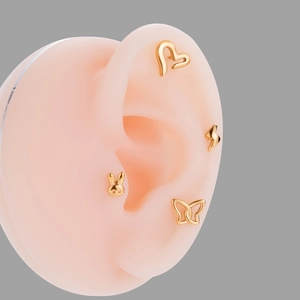Detailed view of four golden stainless steel stud earrings with heart and butterfly shapes
