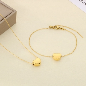 Vue détaillée de l'ensemble collier et bracelet cœur plaqué or 18 carats sur texture