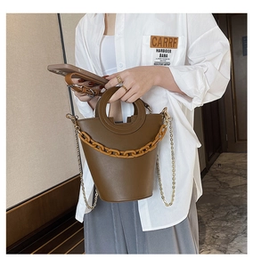 Detail of brown leather tote bag with round handle and thick decorative chain link