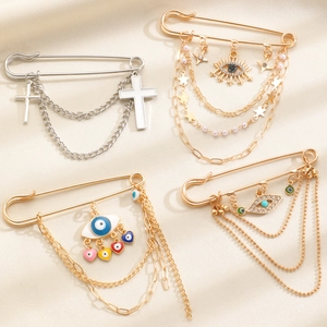 Assorted gold and silver safety pin brooches with evil eye, cross and star charms