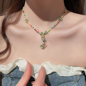 Close-up of colorful beaded necklace with green butterfly pendant worn on neck