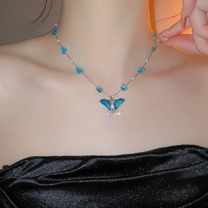 Detalle del collar con colgante de mariposa azul con perlas y cristales brillantes