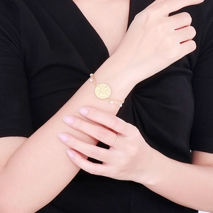 Elegant gold double-layer chain bracelet featuring round coin pendant and white pearls