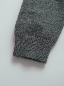 Detail of soft grey knit sweater showing ribbed cuffs and fine wool blend texture