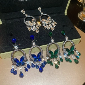 Detail of luxury teardrop tassel earrings with blue and green crystals on black velvet